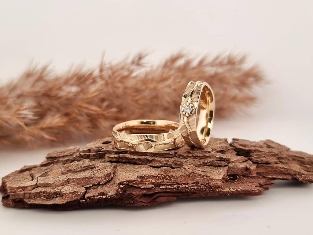 Gouden natural trouwringen met bladmotief en diamant in de damesring